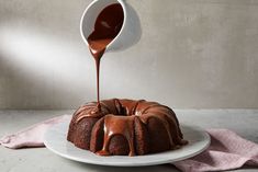 a bundt cake with chocolate icing being drizzled over it on a plate