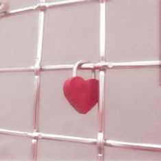 a red heart hanging on the side of a metal wall with bars attached to it