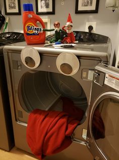 an elf is sitting on top of a washing machine with his head in the washer