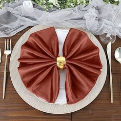 a table setting with silverware, napkins and red bow - tie napkins