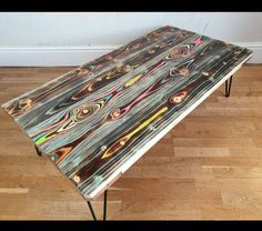 a table that has been painted with different colors and designs on it, sitting on a hard wood floor