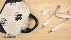 a white and black purse sitting on top of a wooden table next to a lanyard