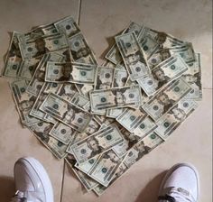 a heart made out of money sitting on the floor next to someone's feet