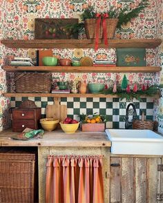 an old fashioned kitchen with floral wallpaper and wooden shelves filled with fruit, vegetables, and other items