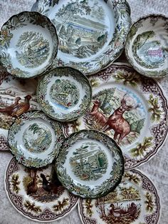 a bunch of plates sitting on top of a white tablecloth covered table next to each other