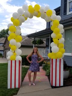 a woman standing in front of an american flag arch with yellow and white balloons on it