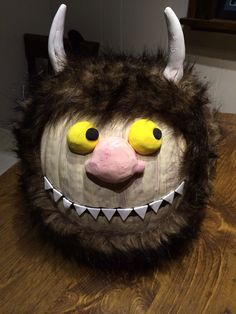 a close up of a stuffed animal head on a wooden table with wood grains