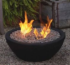 a fire pit sitting on top of gravel next to a planter filled with rocks