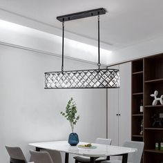 a dining room table with four chairs and a vase on the top of it in front of a bookshelf