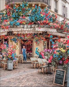 a man standing in front of a flower shop with lots of flowers hanging from the roof