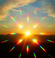 the sun is shining brightly in the sky over some hills and mountains, with bright colored beams