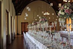 a long table is set up with many glasses and vases on it for a formal function