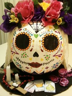 a decorated sugar skull with flowers on it's head sitting on top of a table