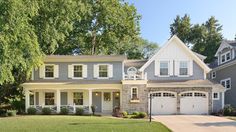 a large gray house with white shutters and two garage doors on the front porch