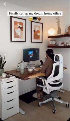 a person sitting at a desk in front of a computer on top of a wooden table