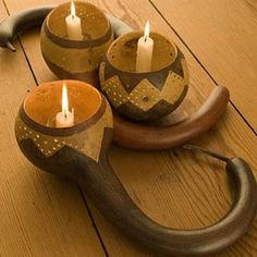 three candles sitting on top of a wooden table next to an elephant's head