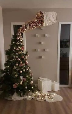 a decorated christmas tree sitting in the middle of a living room with presents on the floor