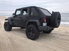 a black jeep is parked on the beach