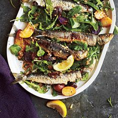 fish and vegetables on a plate with lemon wedges