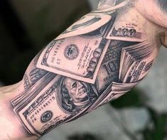 a man's arm with money tattoos on it