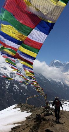 there are many colorful flags flying high in the air on top of a snowy mountain