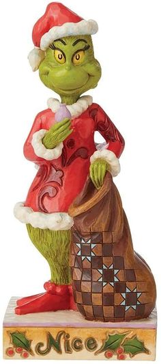 a christmas grin figurine sitting on top of a wooden box holding a bag