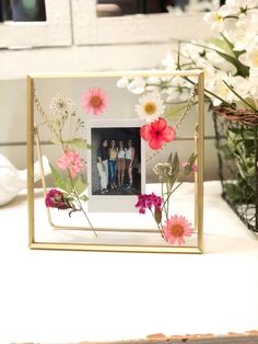 a photo frame with flowers in it sitting on a table