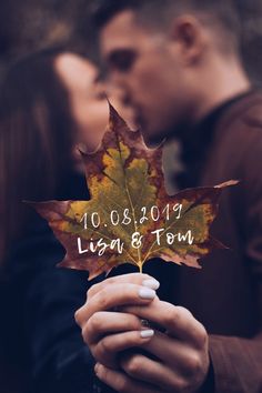 a couple kissing and holding a leaf with the date written on it in front of them