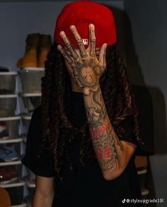 a person with long hair wearing a red hat and holding his hands up to their face