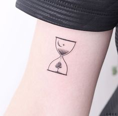 a tattoo on the arm of a woman with a tree in an hourglass design