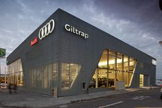 the exterior of a car dealership with cars parked in front and across the street