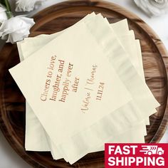 four napkins sitting on top of a wooden plate with white flowers in the background