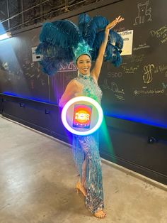 a woman in a blue dress is holding a neon light up ring around her neck