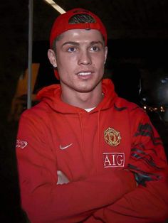 a man in a red hoodie and cap with his arms crossed looking at the camera