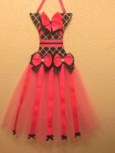 a dress made out of tulle with bows on the front and back, hanging up against a wall