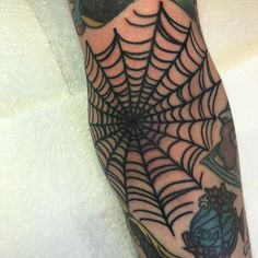 a spider web tattoo on the leg of a person's arm, with other tattoos around it