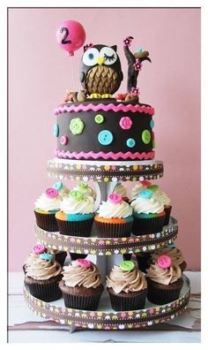 a three tiered cake with cupcakes and an owl on top