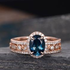 a blue and white diamond ring sitting on top of a rock