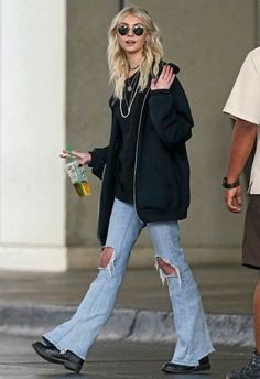 the blonde woman is walking down the street with her hand in her pocket and wearing ripped jeans