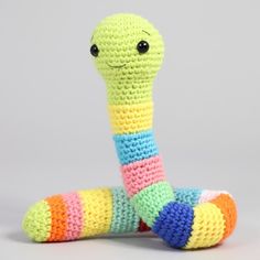 a crocheted snake sitting on top of a white floor next to a gray wall