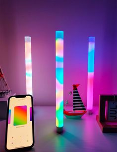 an iphone is sitting next to some colorful lights in a room with other items on the table