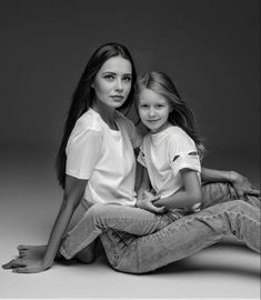 mother and daughter sitting on the floor posing for a black and white photo with their arms around each other