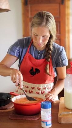 a woman in an apron preparing food on top of a wooden table next to a bottle of milk