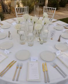 the table is set with white flowers and silverware