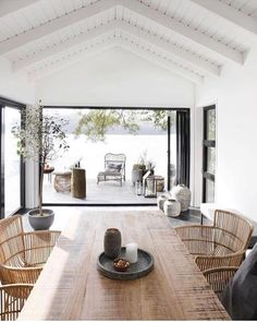 a dining room table with chairs and potted plants on the tables in front of it