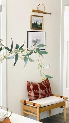 a living room with white walls and pictures on the wall above a wooden bench in front of a window