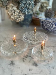 three clear glass candle holders on a marble table