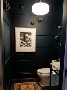 a white toilet sitting in a bathroom next to a sink under a light hanging above it