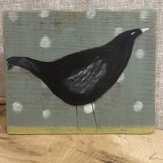 a painting of a black bird sitting on top of a wooden table