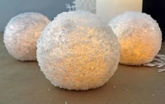 three snowball lights sitting on top of a table next to a white candle holder